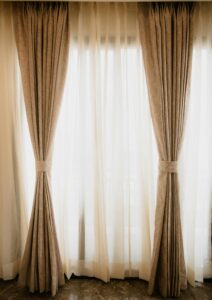 Classy beige curtains and sheer drapes in a sunlit room add elegance and warmth.